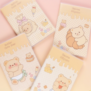 Lot de 4 cahiers de notes lignés avec couvertures illustrées. Deux carnets affichent 'Butter Cute Bear' (ours avec pâtisserie et ours avec nœud), et deux affichent 'Beurre Mignon' (ours avec glace et biscuit, et ours au cœur). Design jaune beurre sur fond dégradé paste
